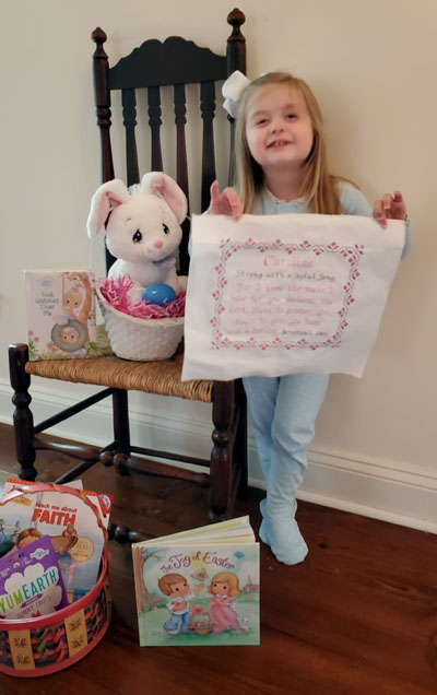 Caroline holding her Name Blessings design stitched by mom Kristin